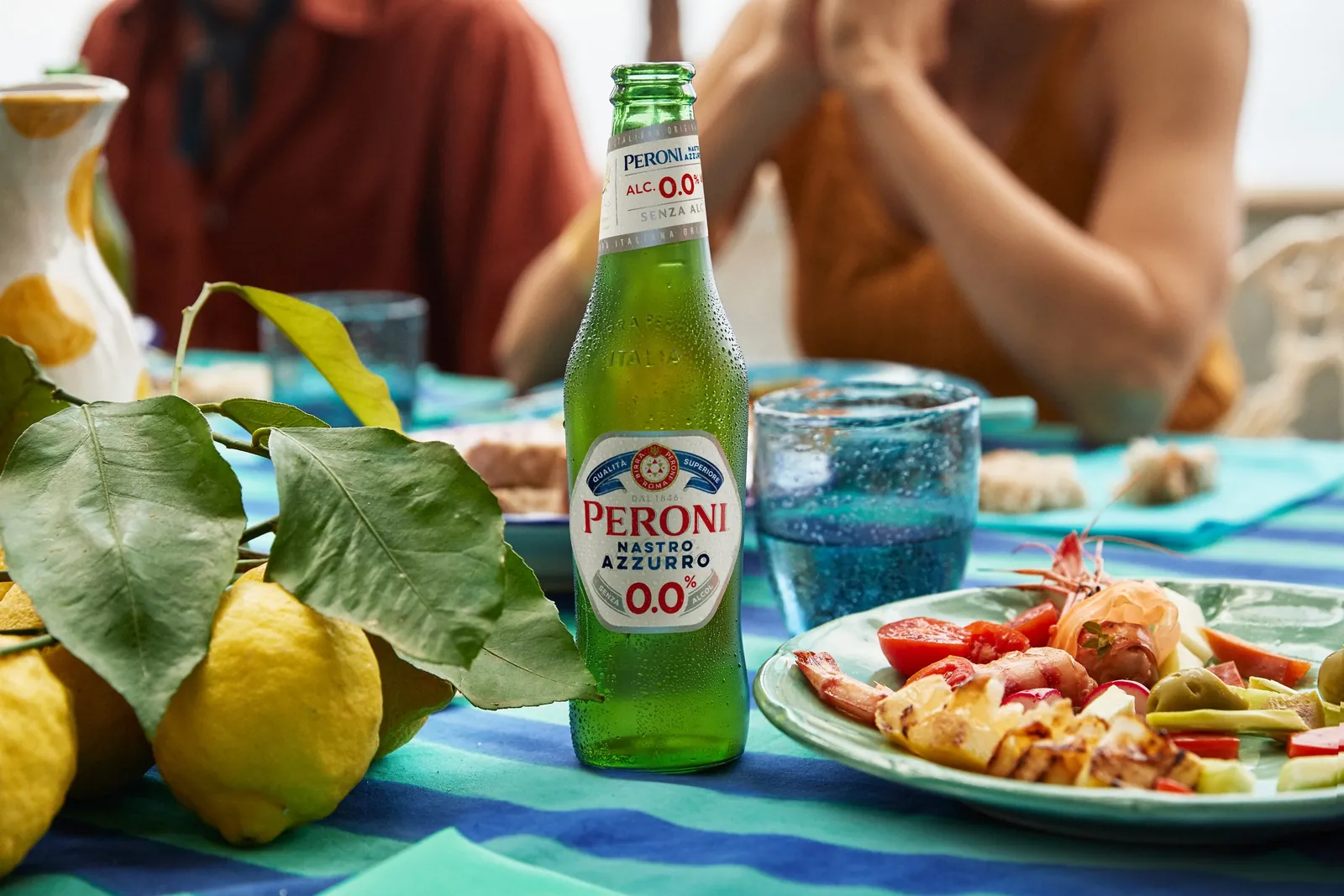 Peroni Nastro Azzurro 0.0 sur une table au soleil, avec des citrons